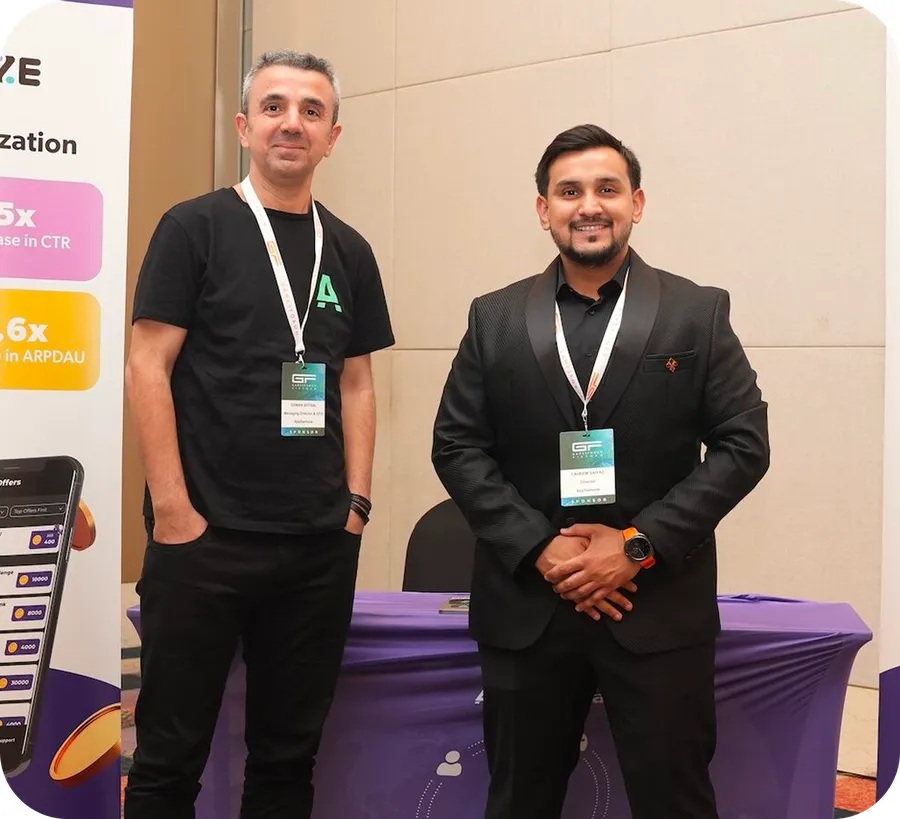 Two AppSamurai team members at an industry event beside an AppsPrize display