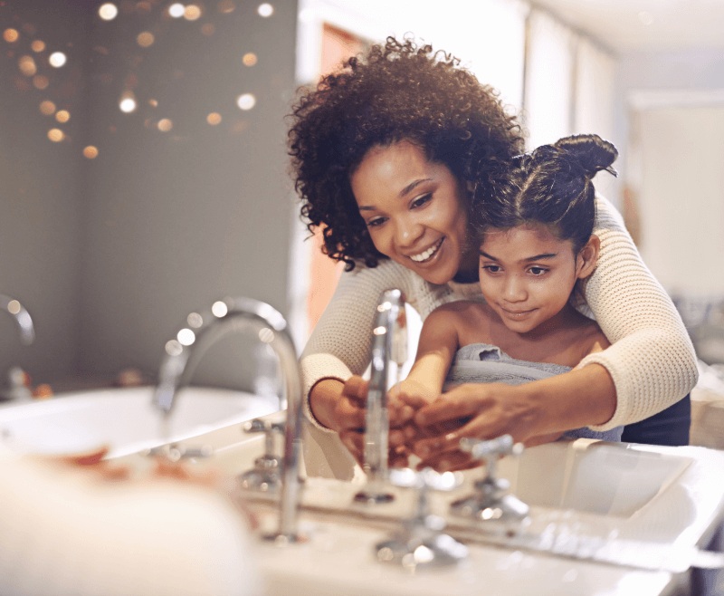 Mother and daughter washing their hands at a bathroom sink