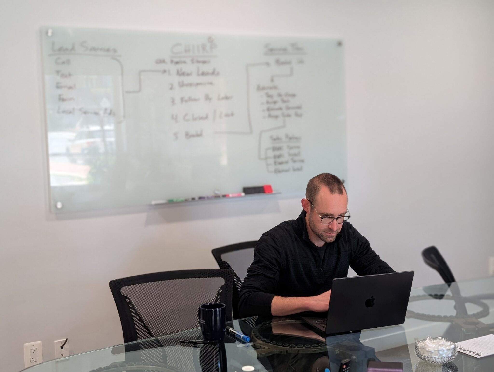 An ArachnidWorks team member works at a laptop in a conference room