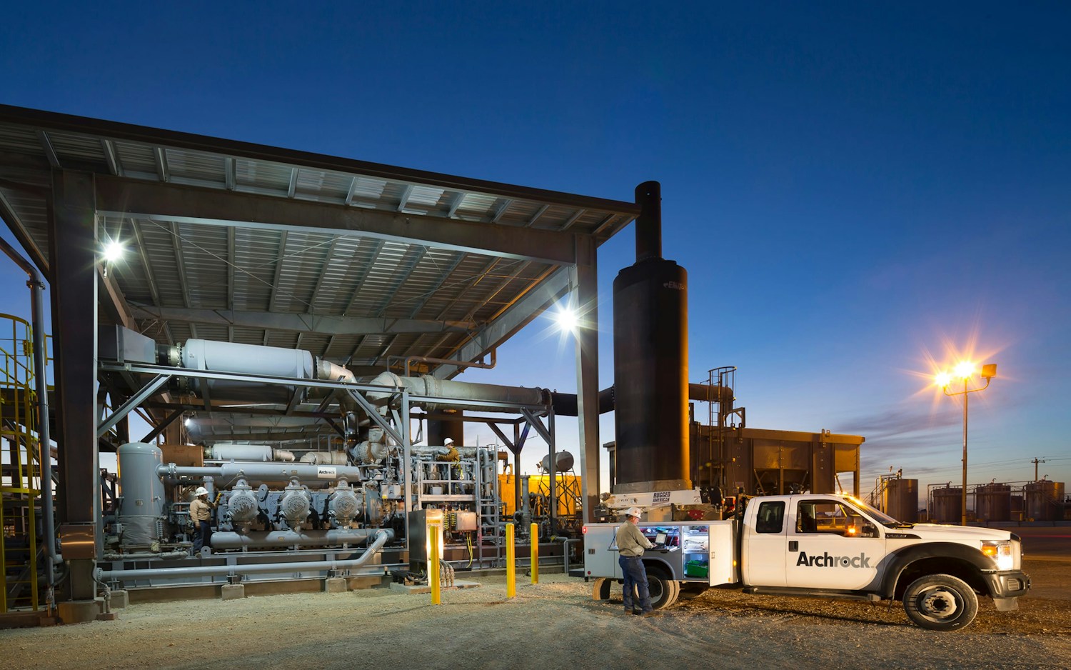 Archrock service vehicle and field worker outside an industrial facility at dusk