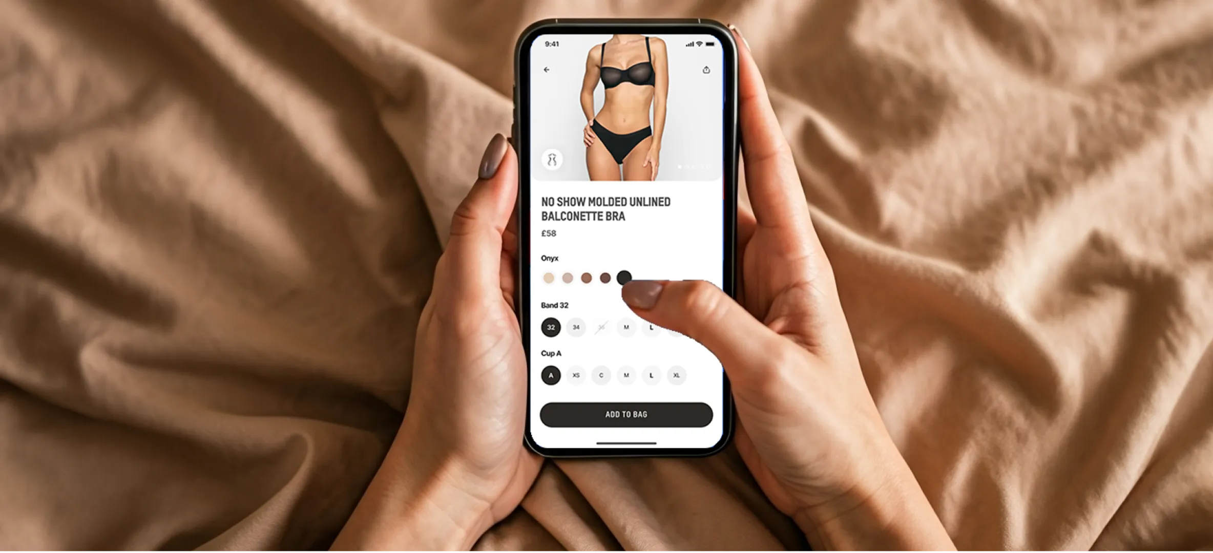 Hands holding a phone displaying the SKIMS shopping app