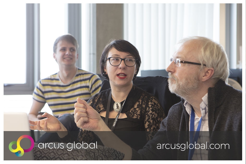 Three Arcus Global colleagues talking in an office