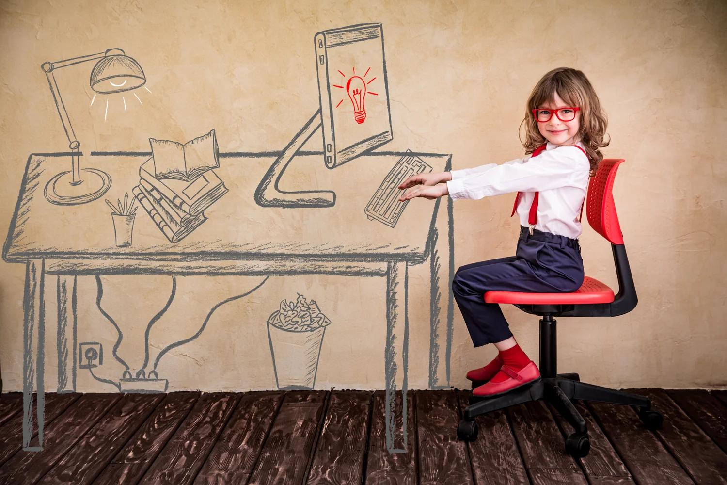 Illustrative photograph of a child seated beside a desk and computer drawn on a wall