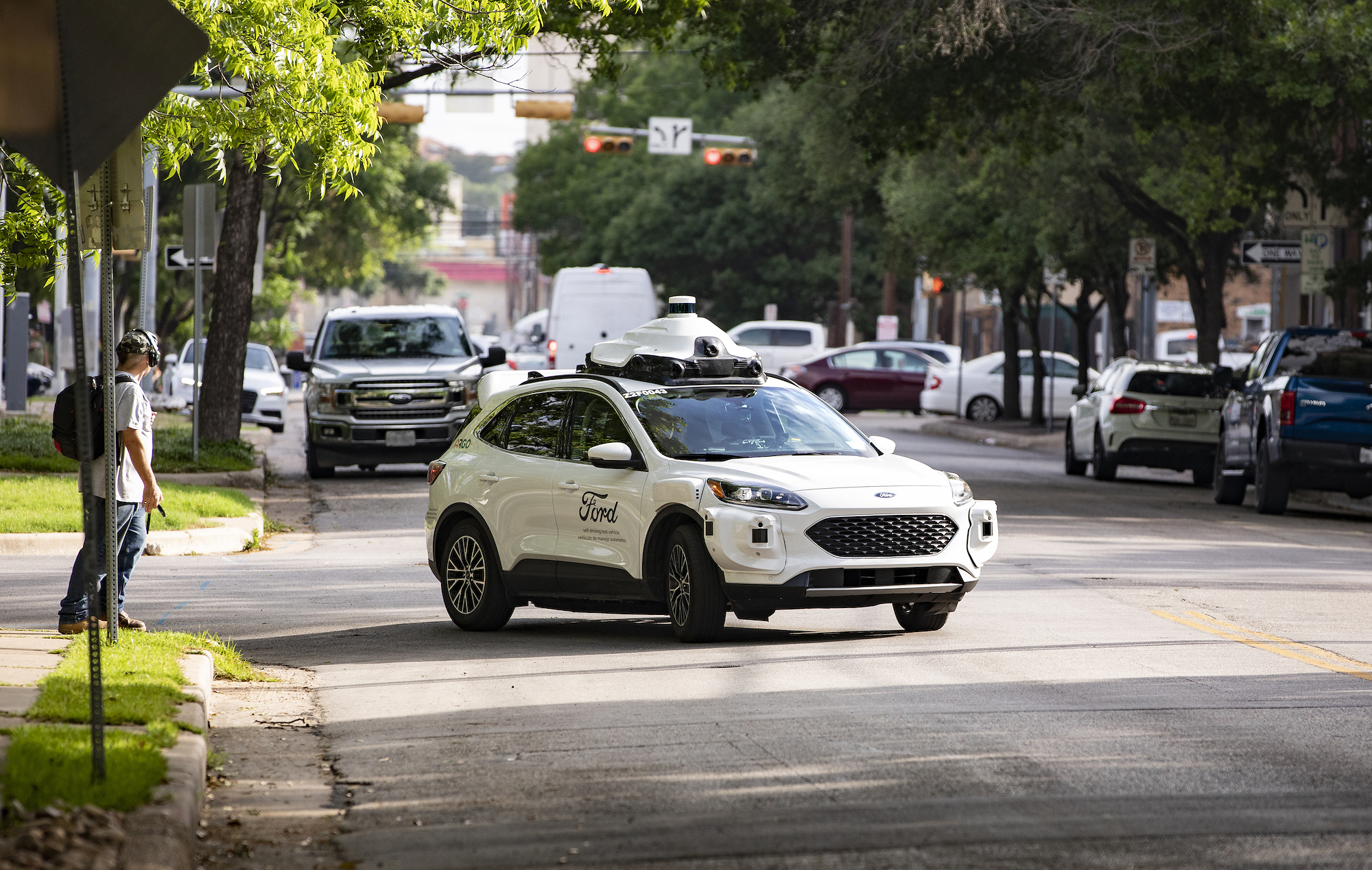 Argo-equipped Ford Escape on an urban street with traffic and pedestrians