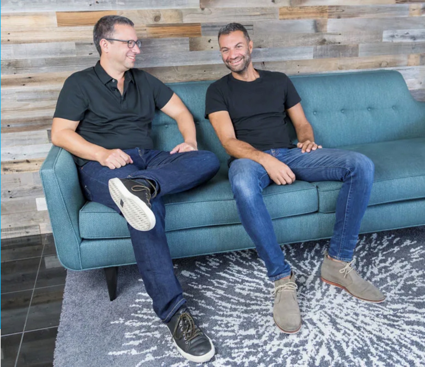 Ilan Twig on the left and Ariel Cohen on the right, seated together on a teal sofa