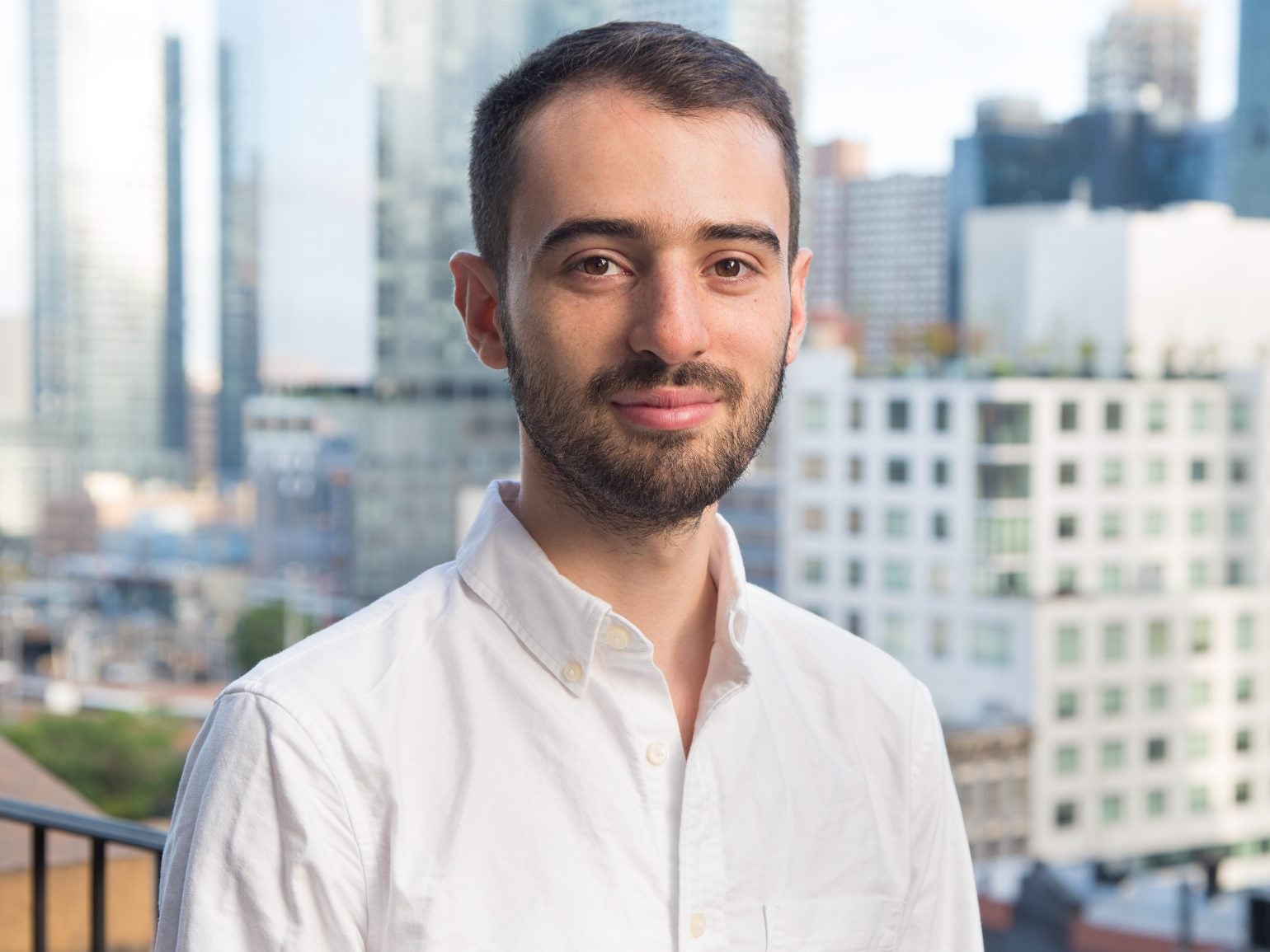 Ariel Katz standing on a balcony with a city skyline behind him