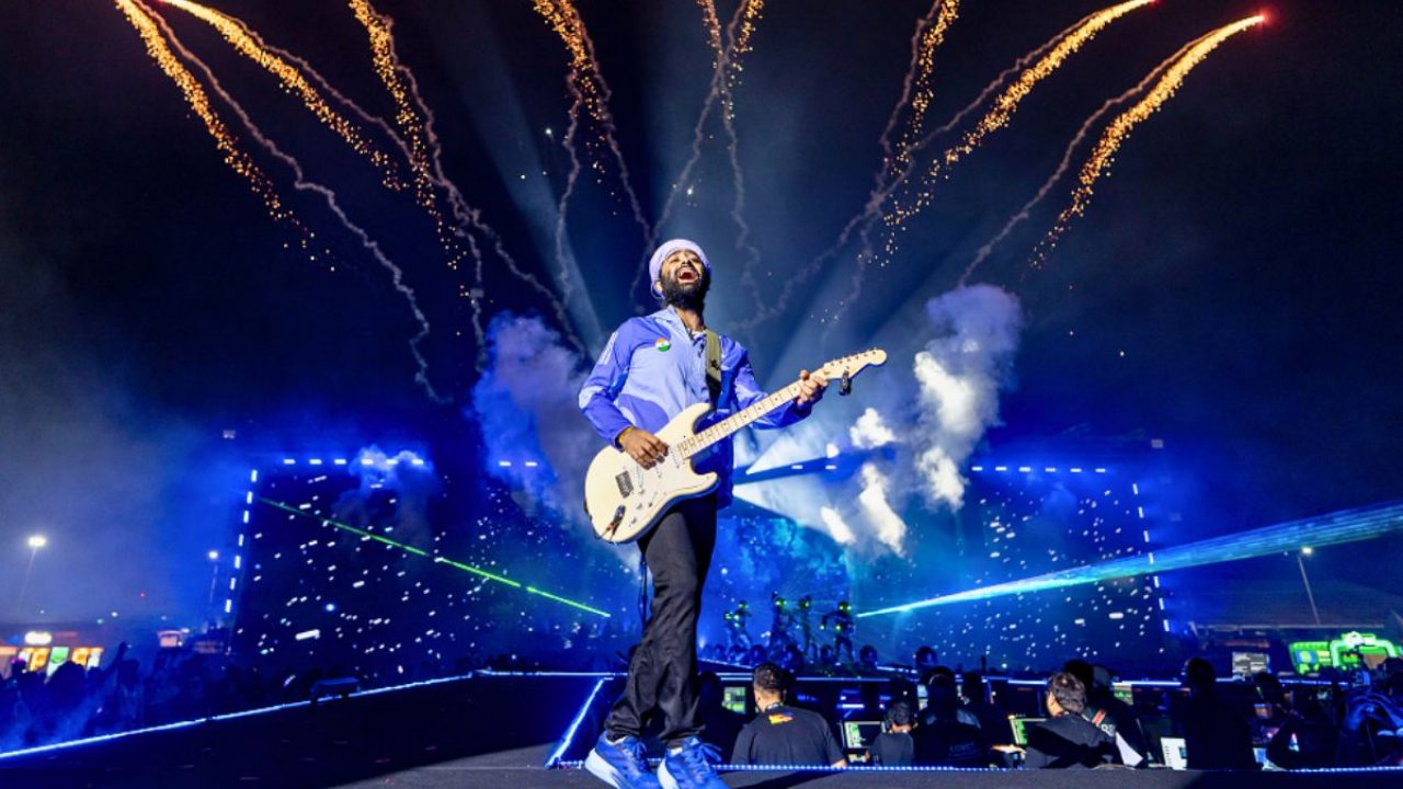 Arijit Singh performing onstage in Hyderabad under blue and purple lights