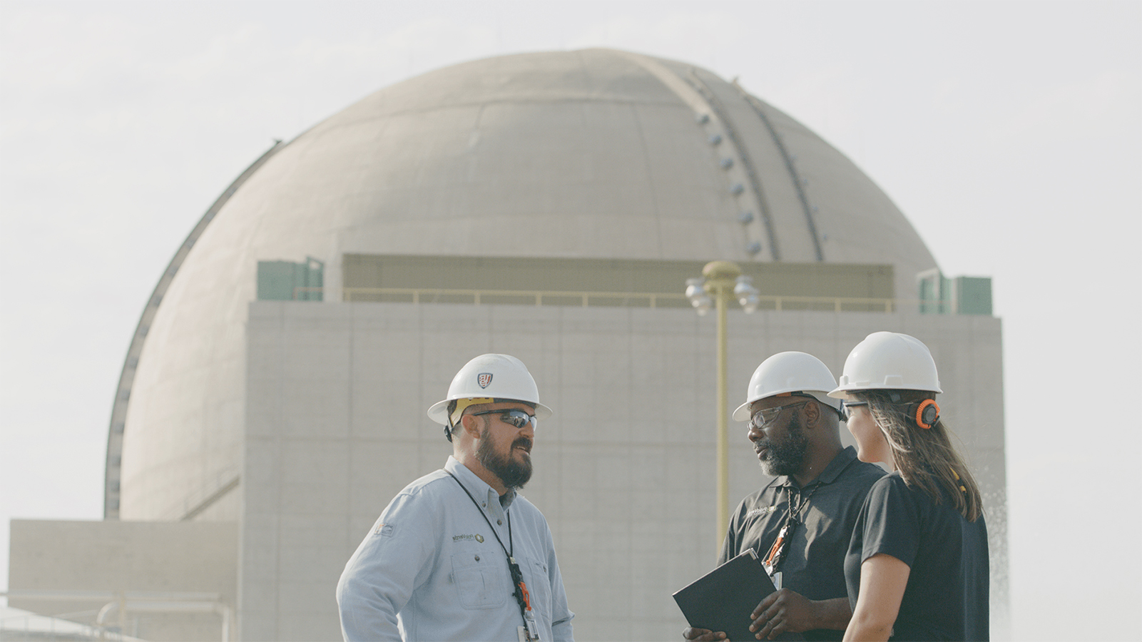 Palo Verde employees standing together beside a nuclear containment structure