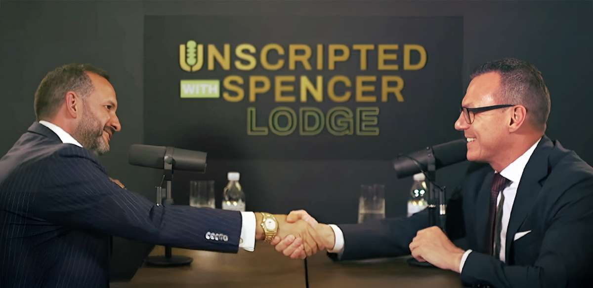 Armand Arton, left, shakes hands with interviewer Spencer Lodge across a podcast table.