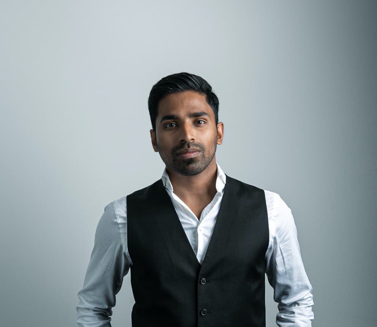 Aroosh Thillainathan wearing a white shirt and dark waistcoat in an archival press portrait