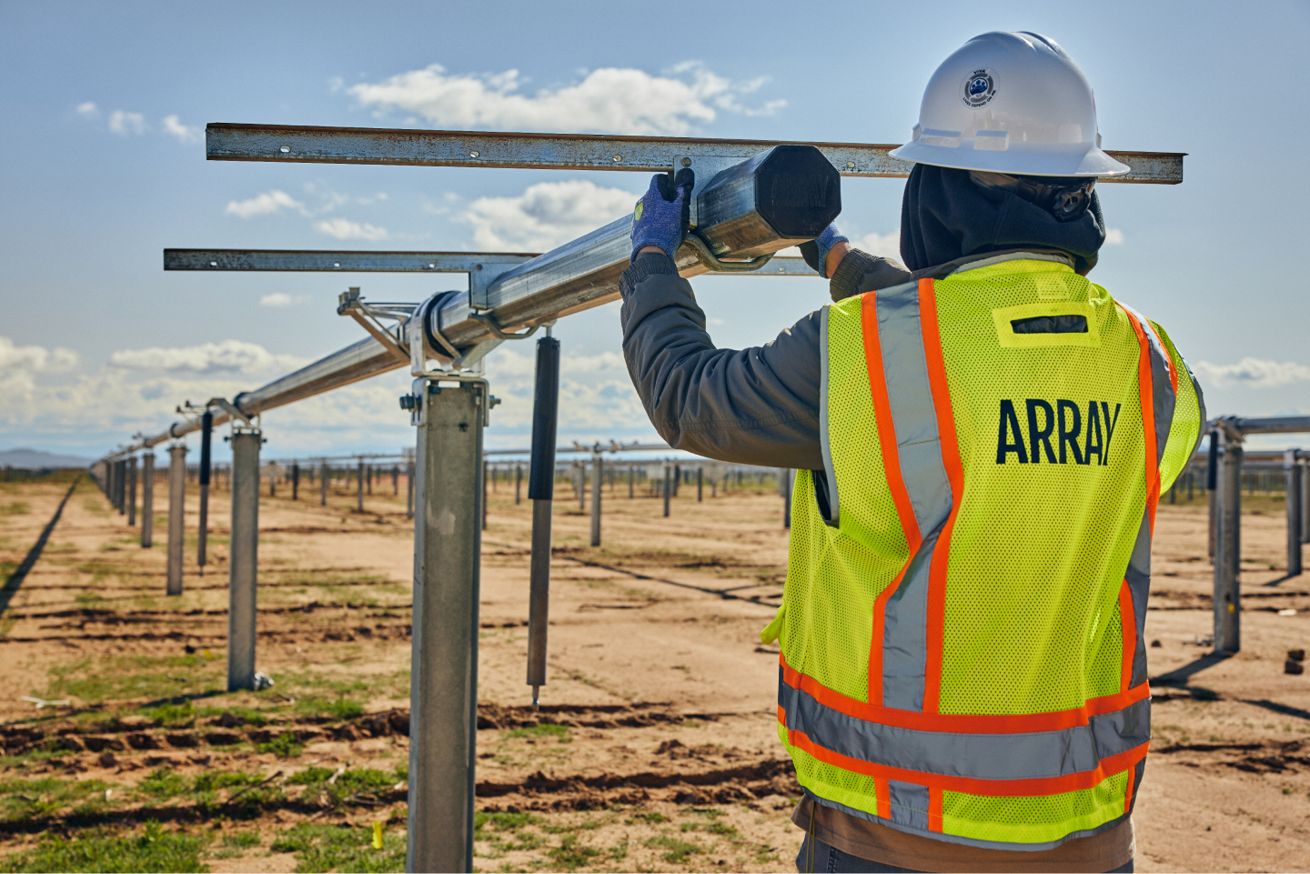 An Array technician installing a structural beam in a solar field