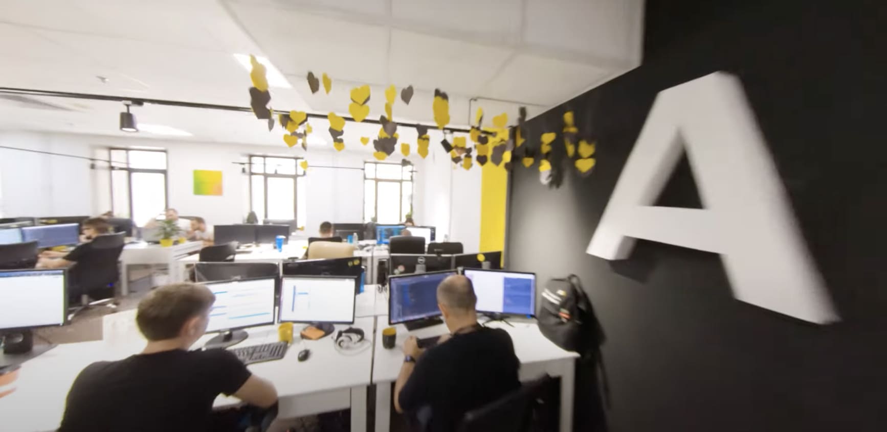 ARTJOKER office with team members working at rows of monitors
