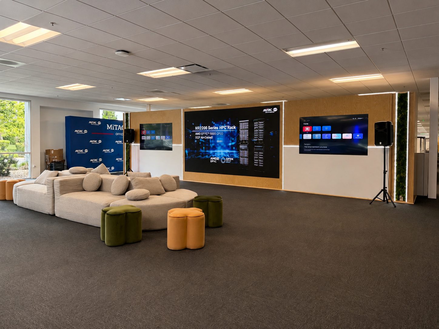 MiTAC customer experience center lounge with sofas, stools, and three large presentation screens