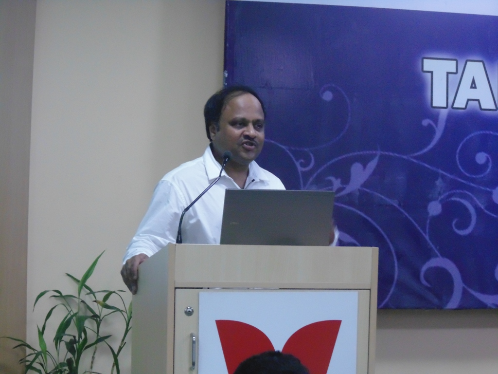 Arun Gollapudi speaking behind a lectern at TAPMI
