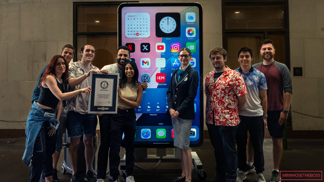 Arun Maini and collaborators stand beside the working giant iPhone with a Guinness World Records certificate