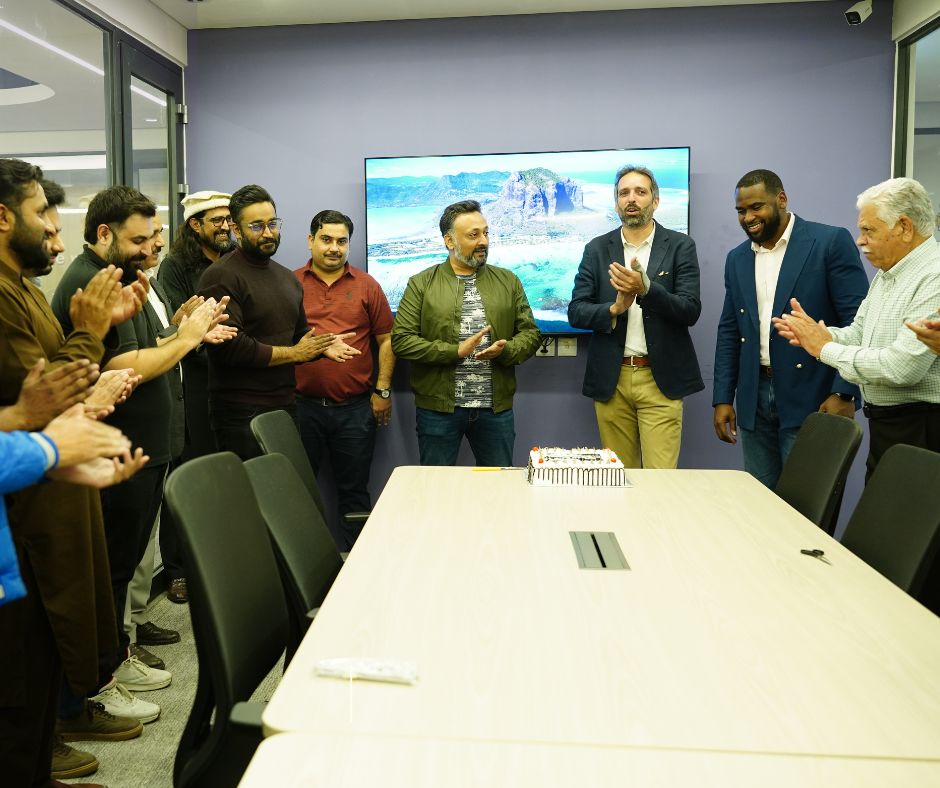 Asadullah Khan and Eplanet colleagues gathered around a table with a celebration cake