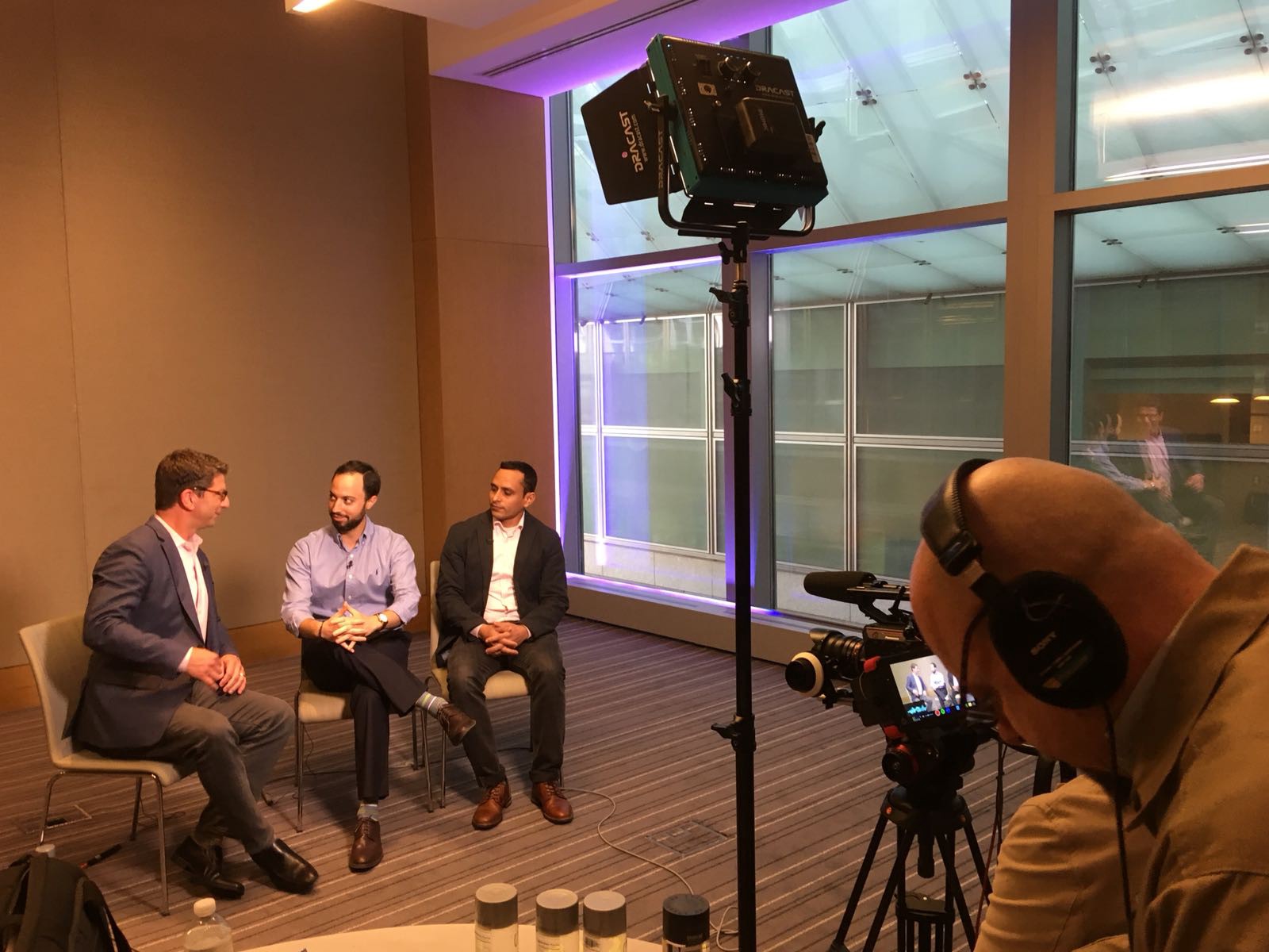 Asaf Meir seated between an interviewer and Solidus Labs CTO Praveen Kumar during a filmed conversation
