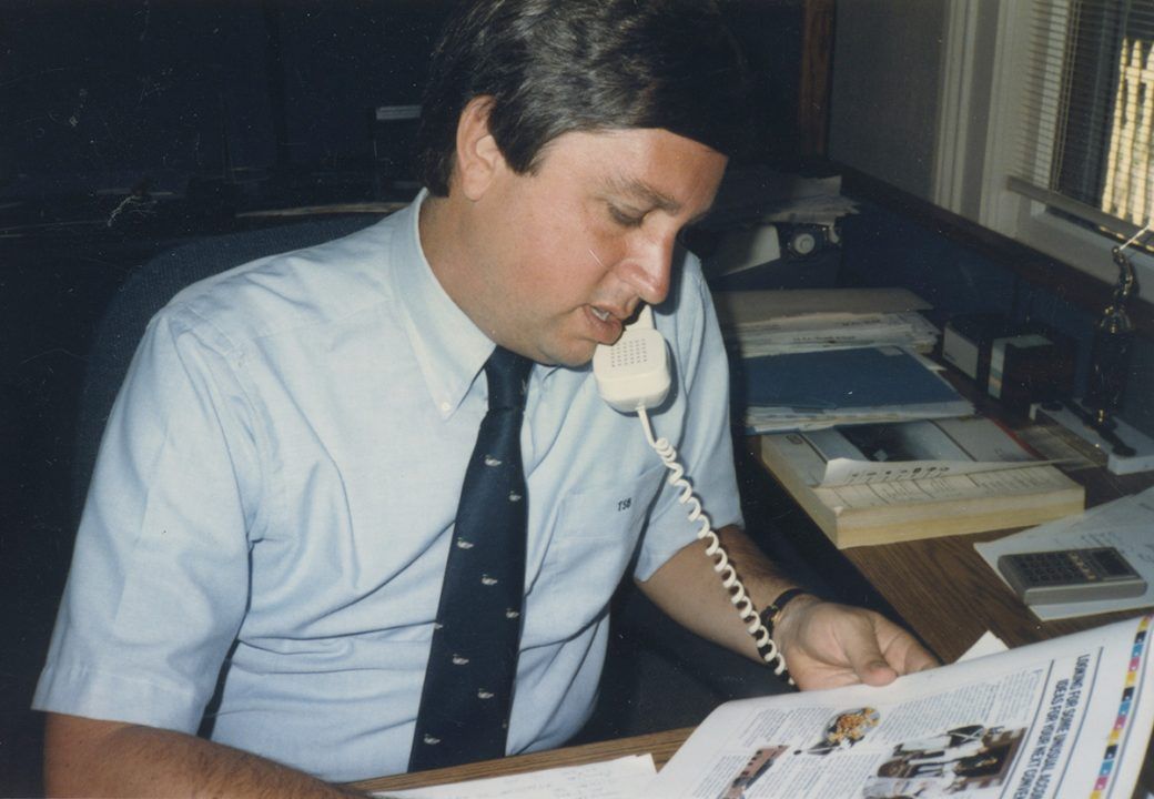 Asher Agency founder Tim Borne reviewing printer proofs on the telephone