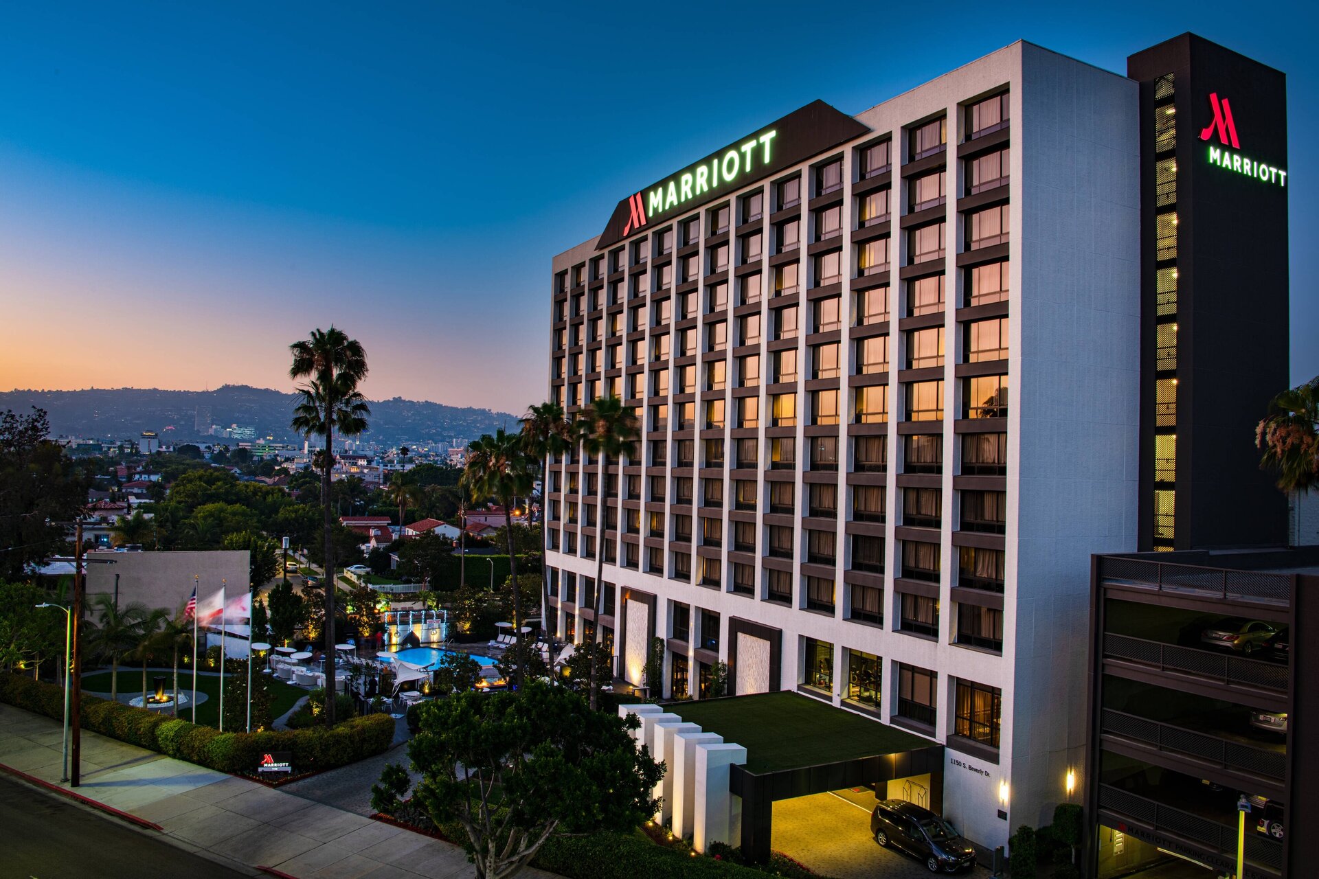 The Beverly Hills Marriott exterior at dusk, with illuminated signage and palm trees