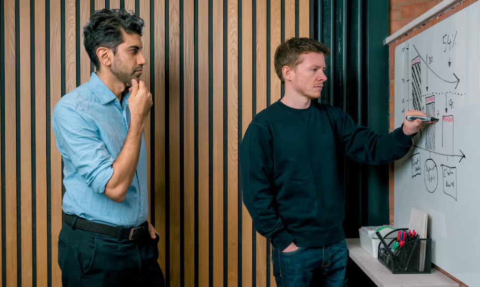 Ashish Mandavia and Lucas Gordon study a diagram on a whiteboard
