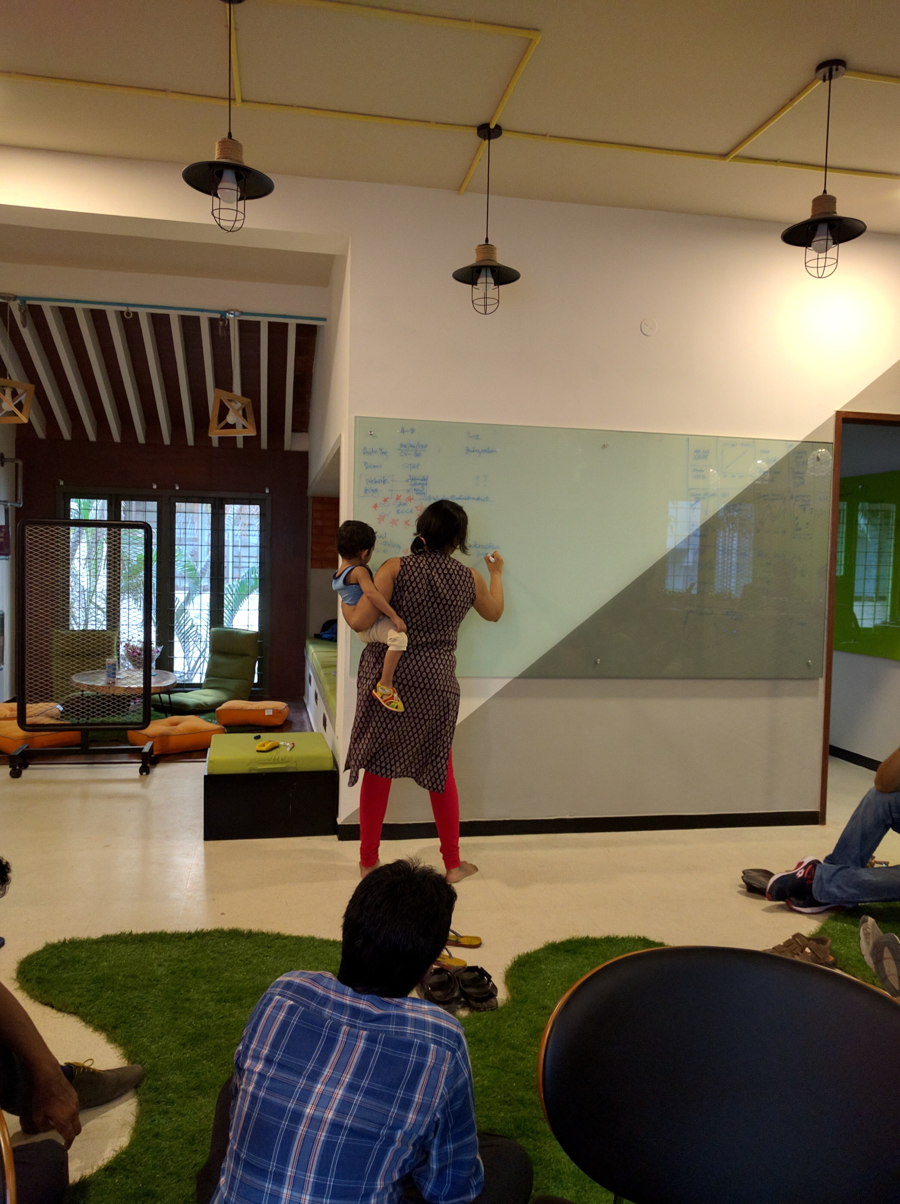Ashwini Asokan writing on an office whiteboard while holding her child in April 2016