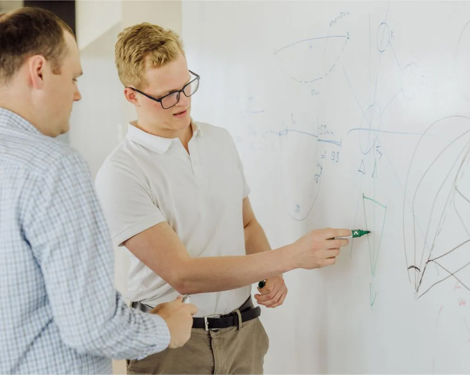 Two ASI team members discussing diagrams on a whiteboard