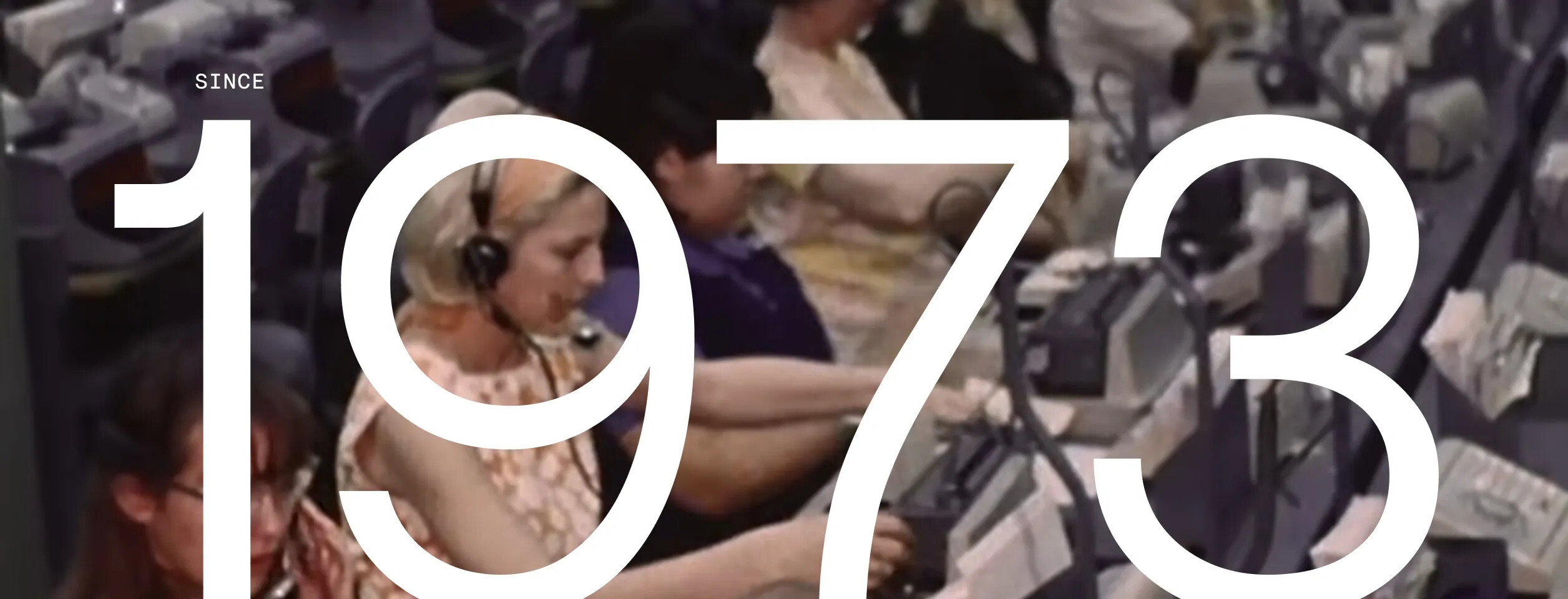 Archival-style image of a busy early call center overlaid with the year 1973