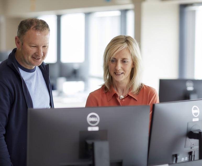 Two Aspen Grove colleagues working together at office monitors