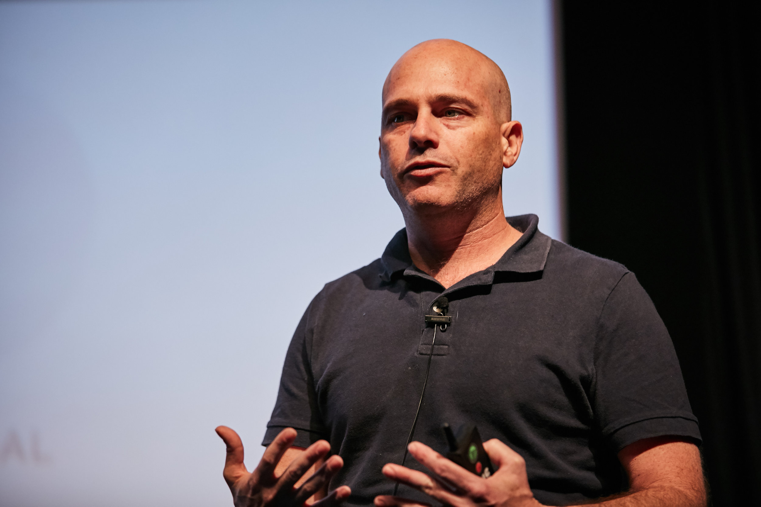Assaf Glazer speaking onstage at the 2018 LDV Vision Summit, holding a presentation remote