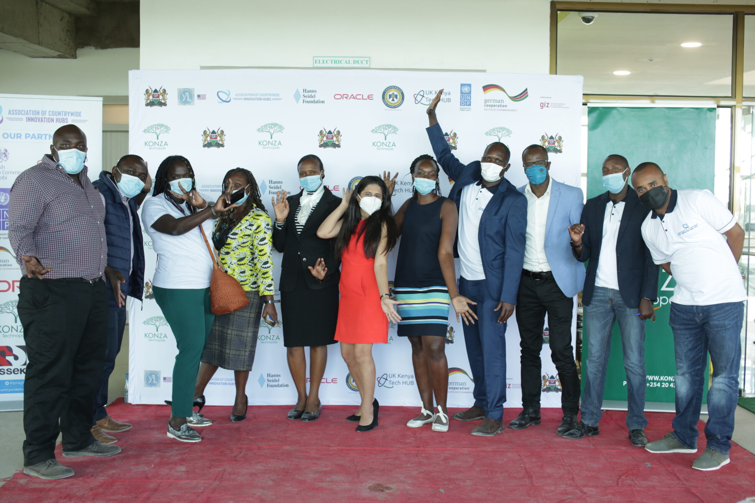Masked participants pose together in front of an ACIH and Konza partnership backdrop