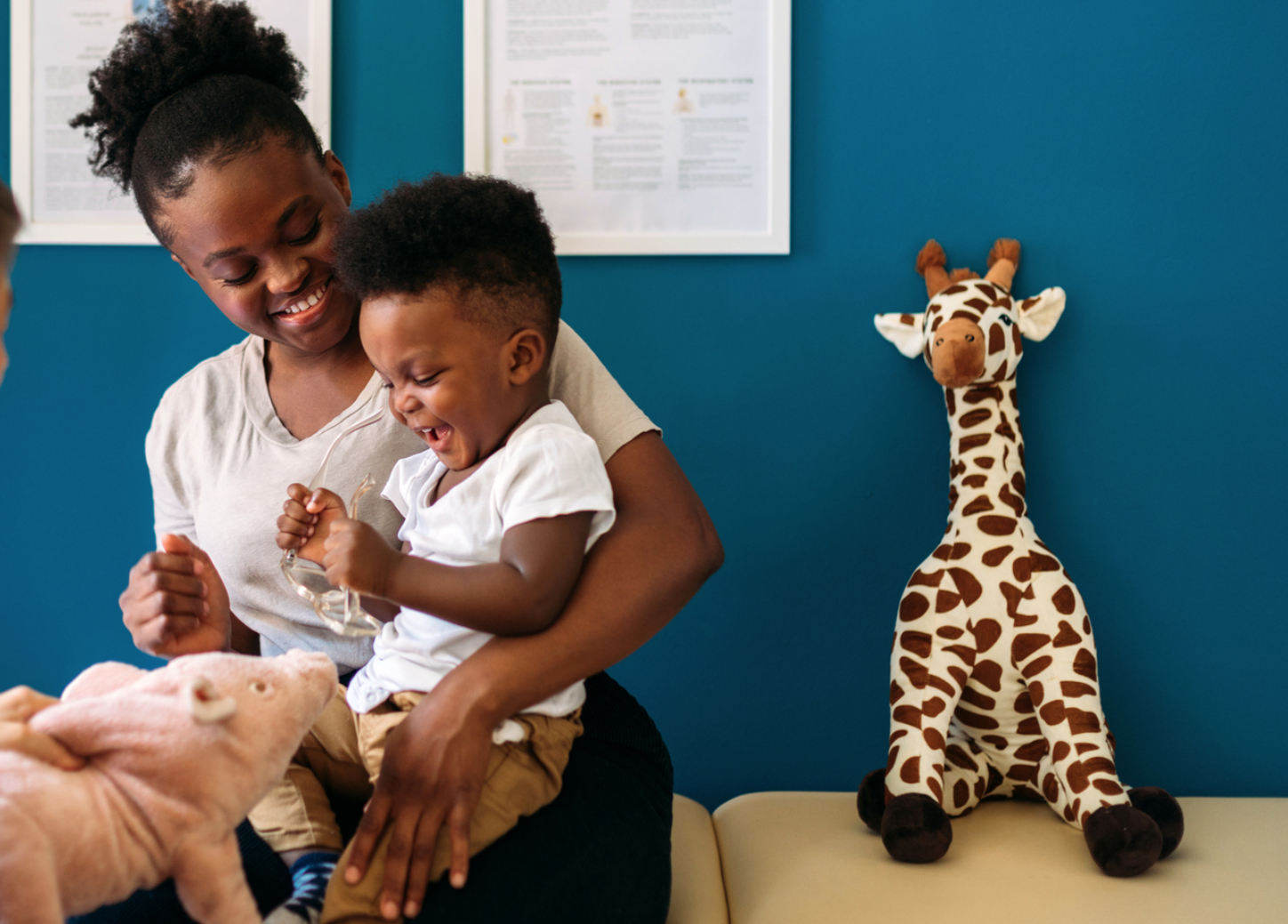 A woman and child beside stuffed animals in healthcare imagery published by Astrana Health