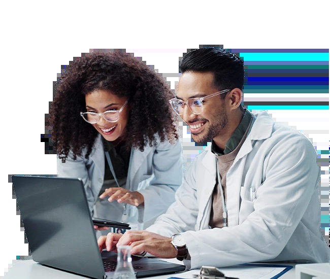 Two laboratory professionals in safety glasses working at laptops