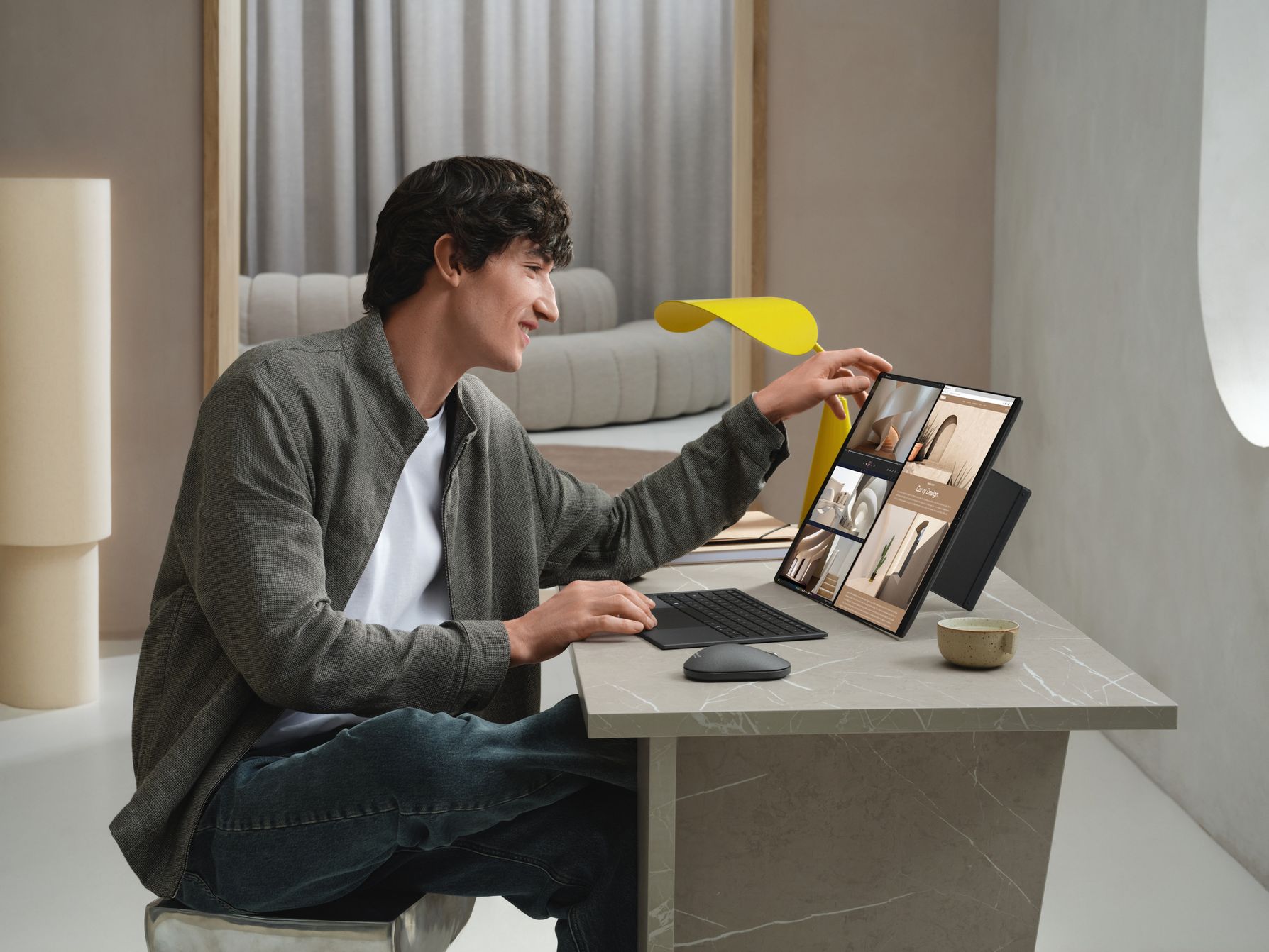 ASUS press photograph of a person using a Zenbook DUO with its two screens upright and the keyboard detached.
