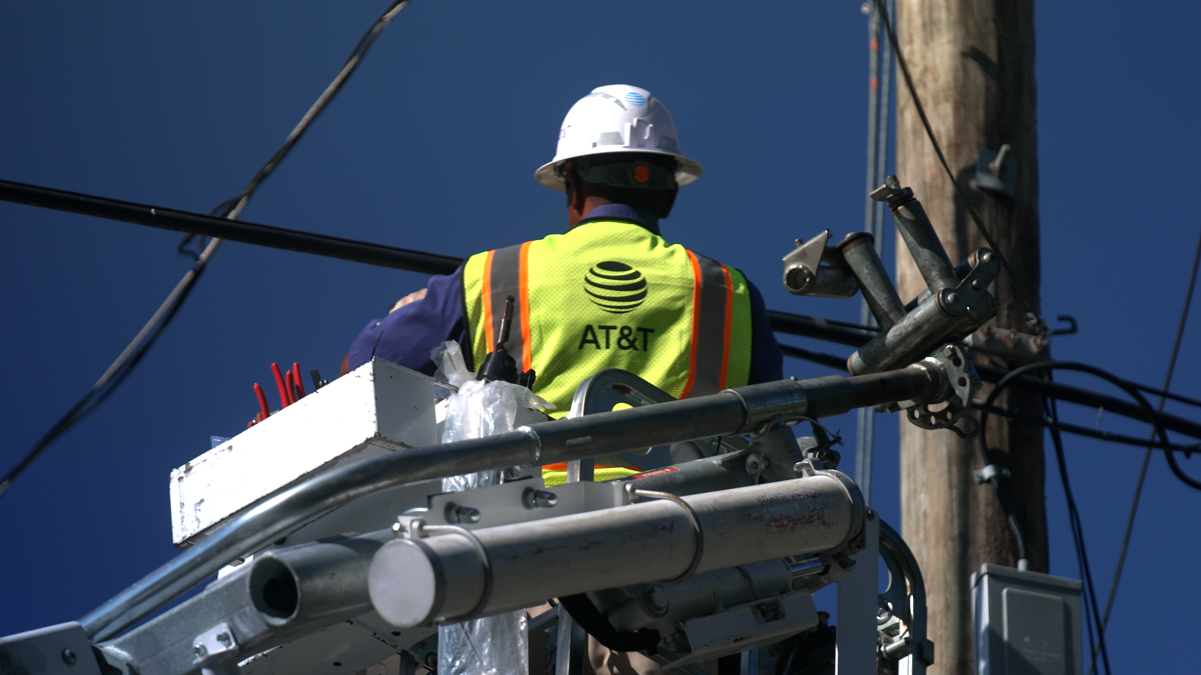 An AT&T technician works from a bucket truck on a fiber deployment