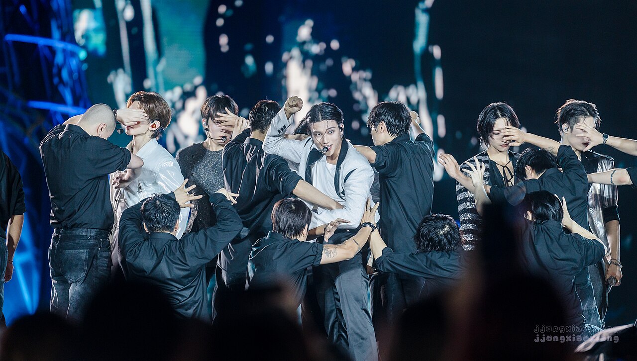 ATEEZ members performing together beneath blue stage lights in New York in 2024