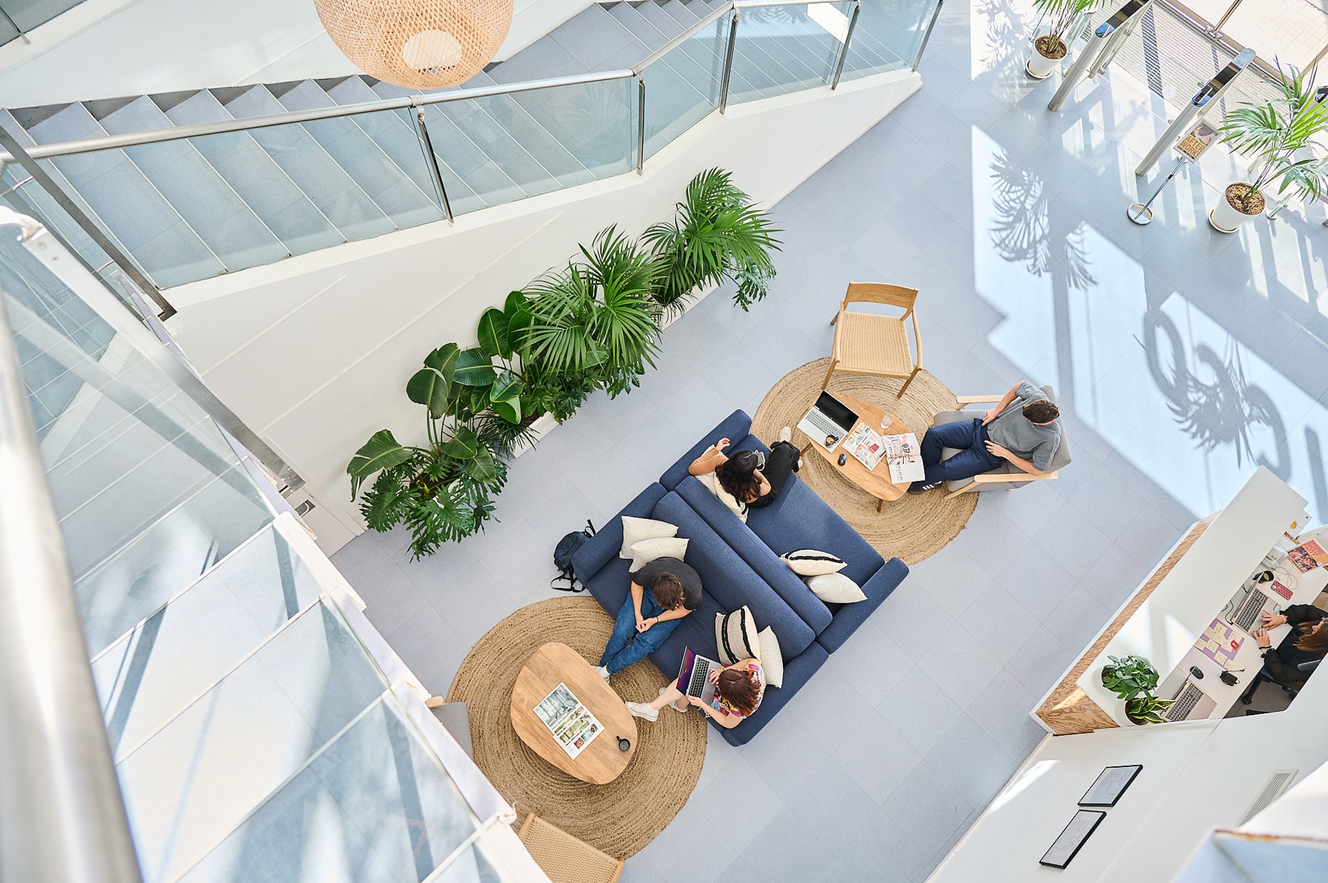 An overhead view of Aticco’s light-filled common area with sofas, plants and people working