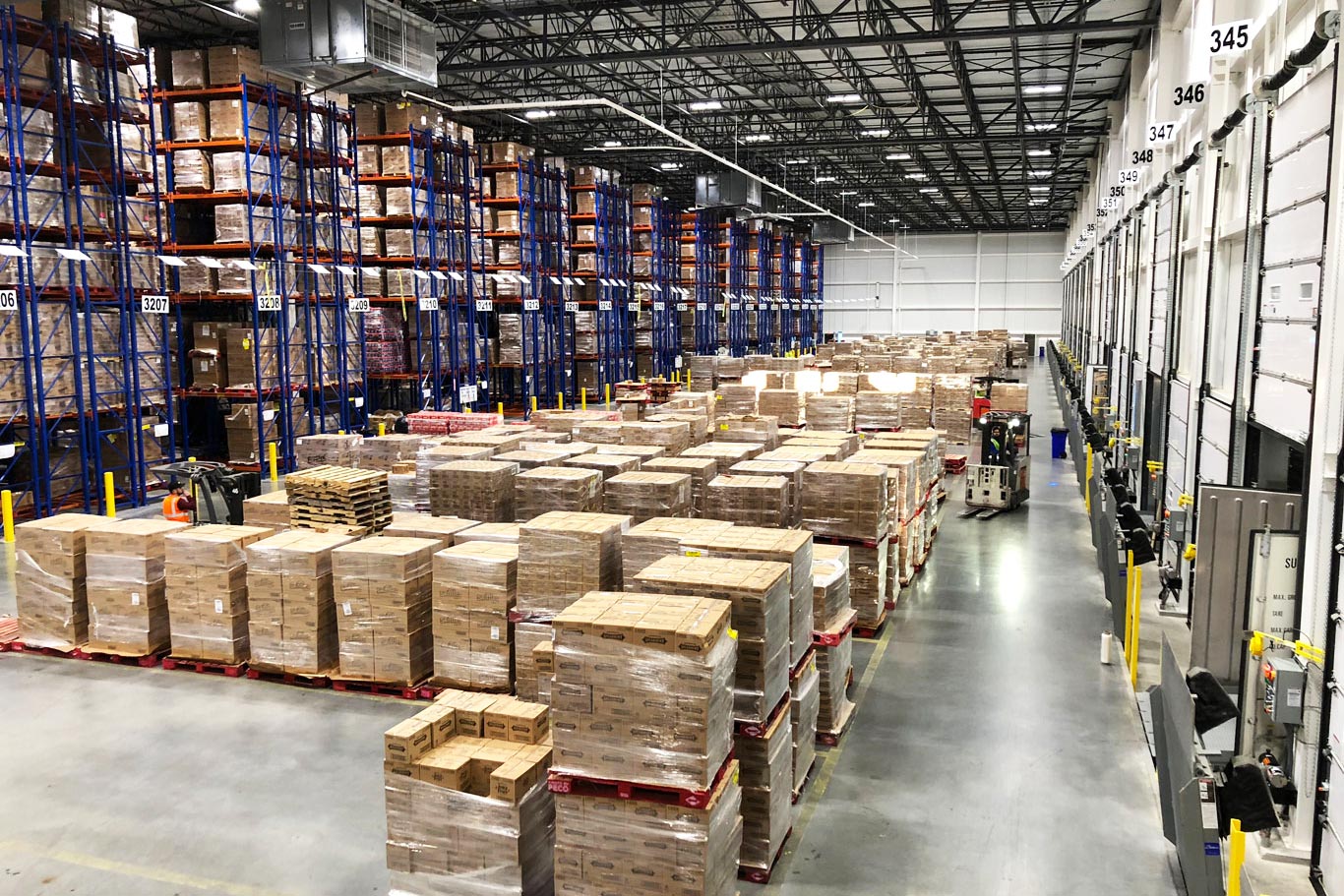 Palletized goods, warehouse racks, loading doors, and forklifts inside an ABW warehouse