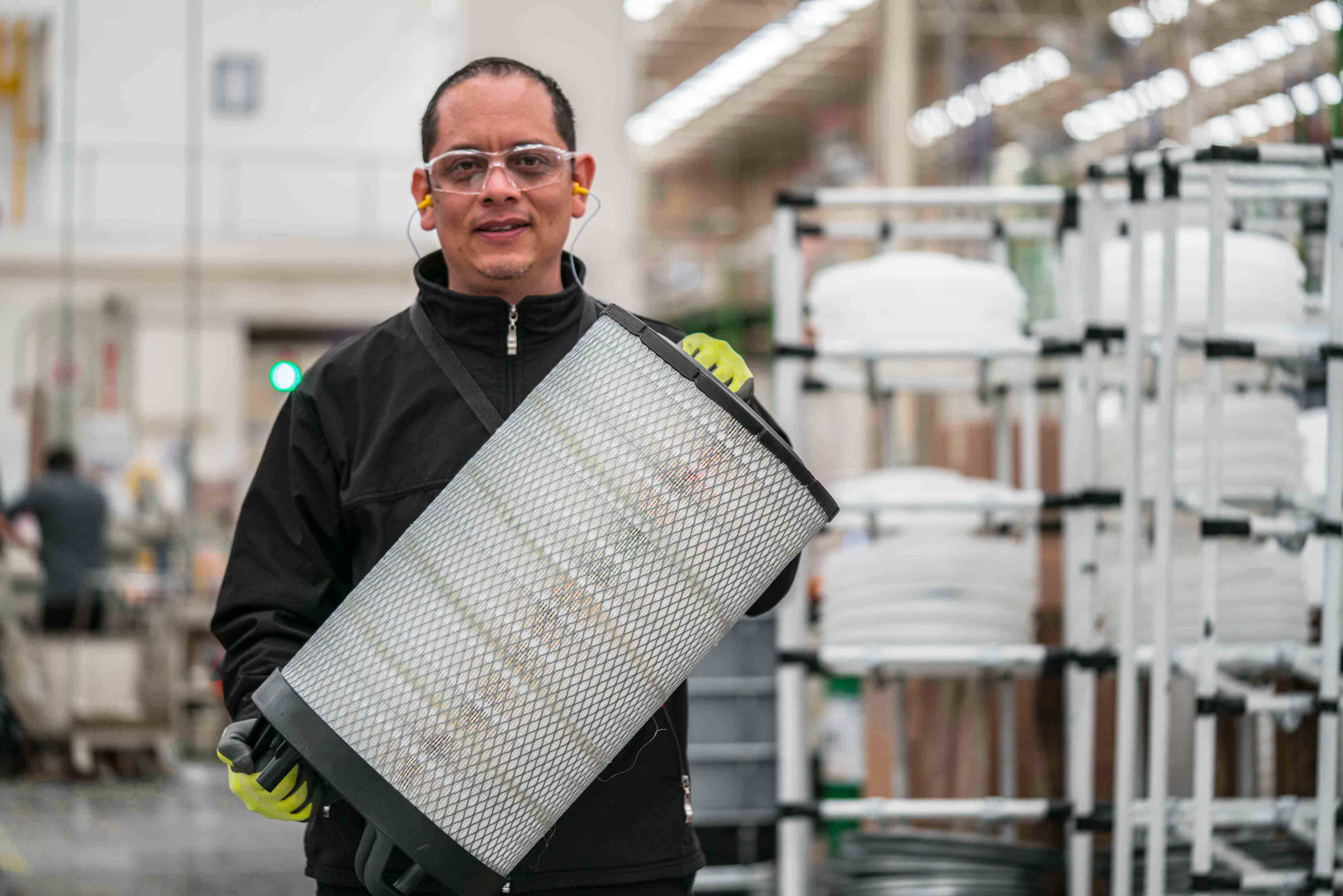 Atmus manufacturing employee holding a Fleetguard filter in a production facility