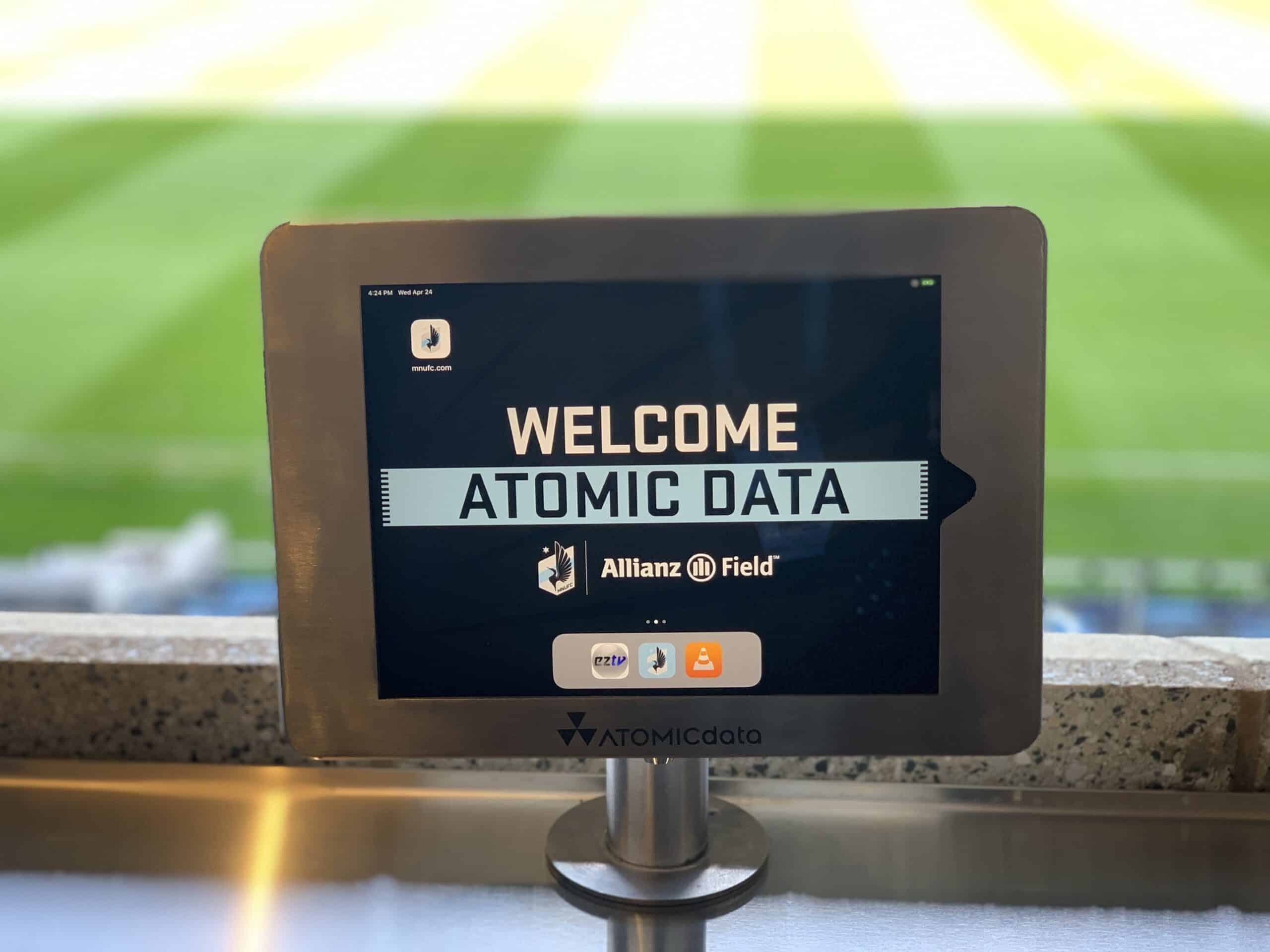 An Atomic Data welcome screen on a tablet overlooking the pitch at Allianz Field