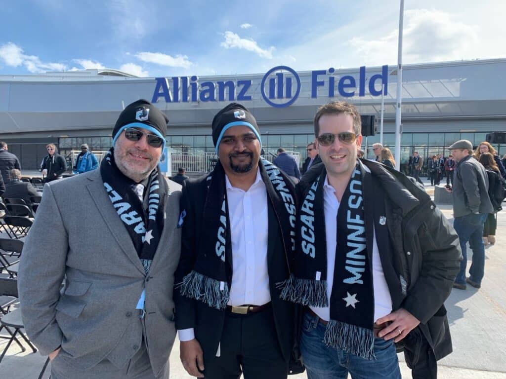 Three people wearing Minnesota United scarves outside Allianz Field