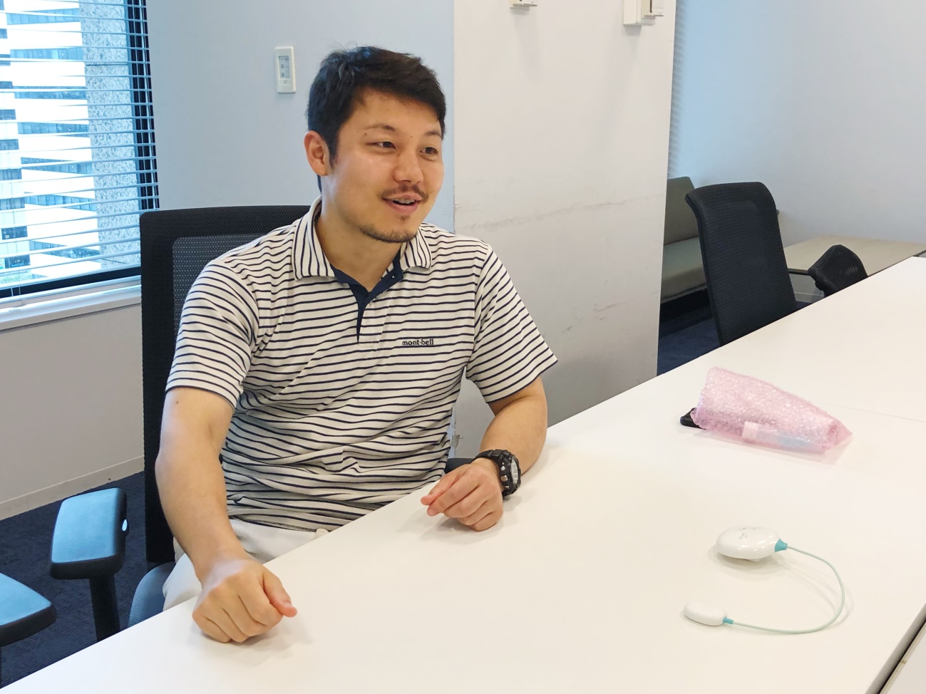 Atsushi Nakanishi seated at a meeting table with an early DFree device