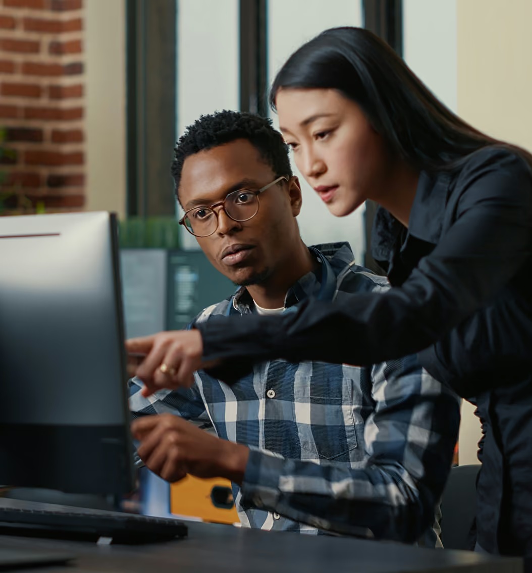 Two coworkers reviewing a computer screen in the workplace image published on Attain’s About page