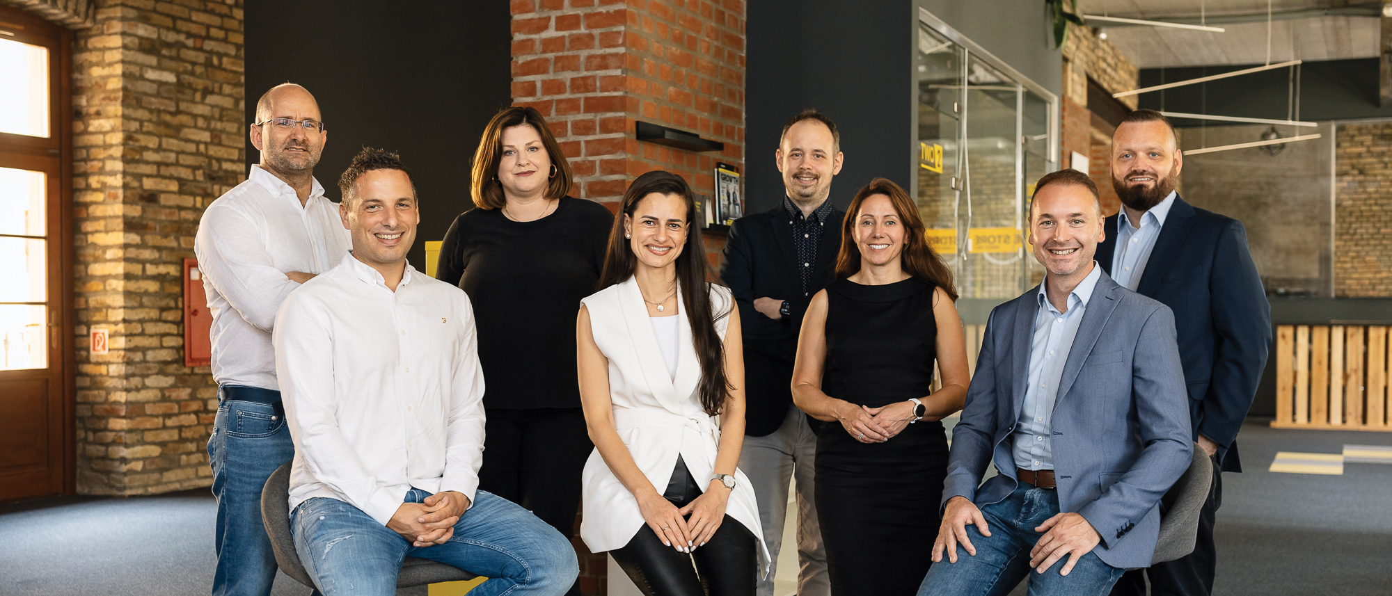 Eight members of Antavo’s leadership team in a brick-walled office, with Attila Kecsmar seated on the right