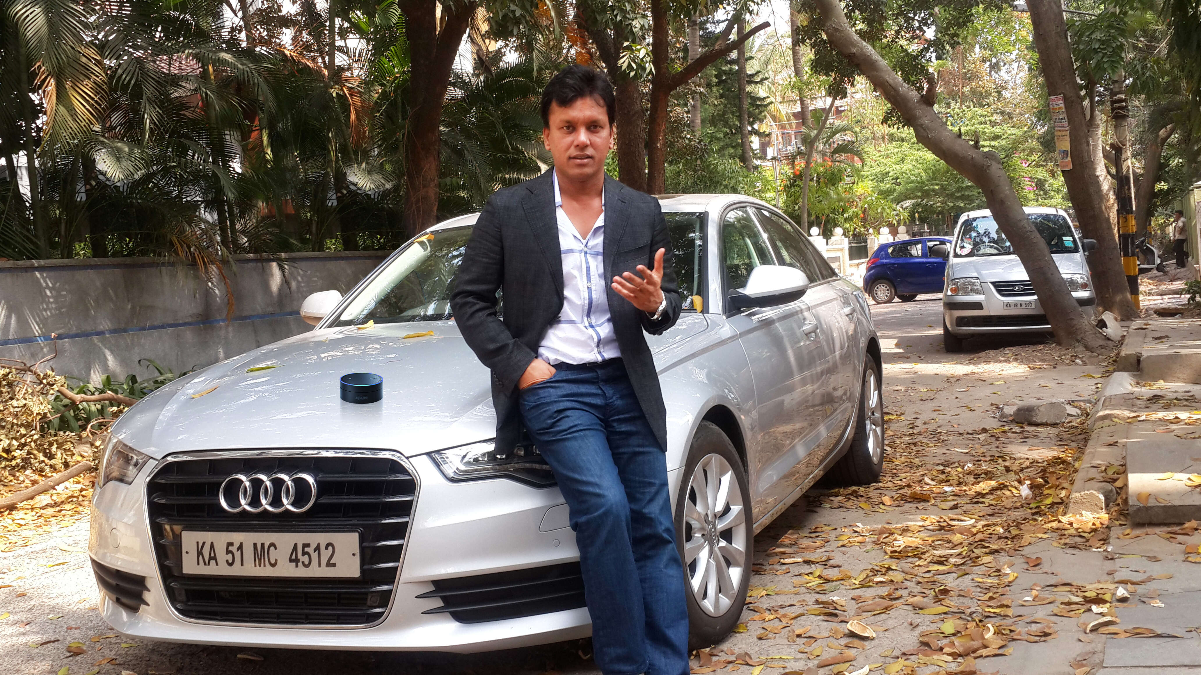 Atul Jalan beside a car with an Amazon Echo Dot resting on its bonnet