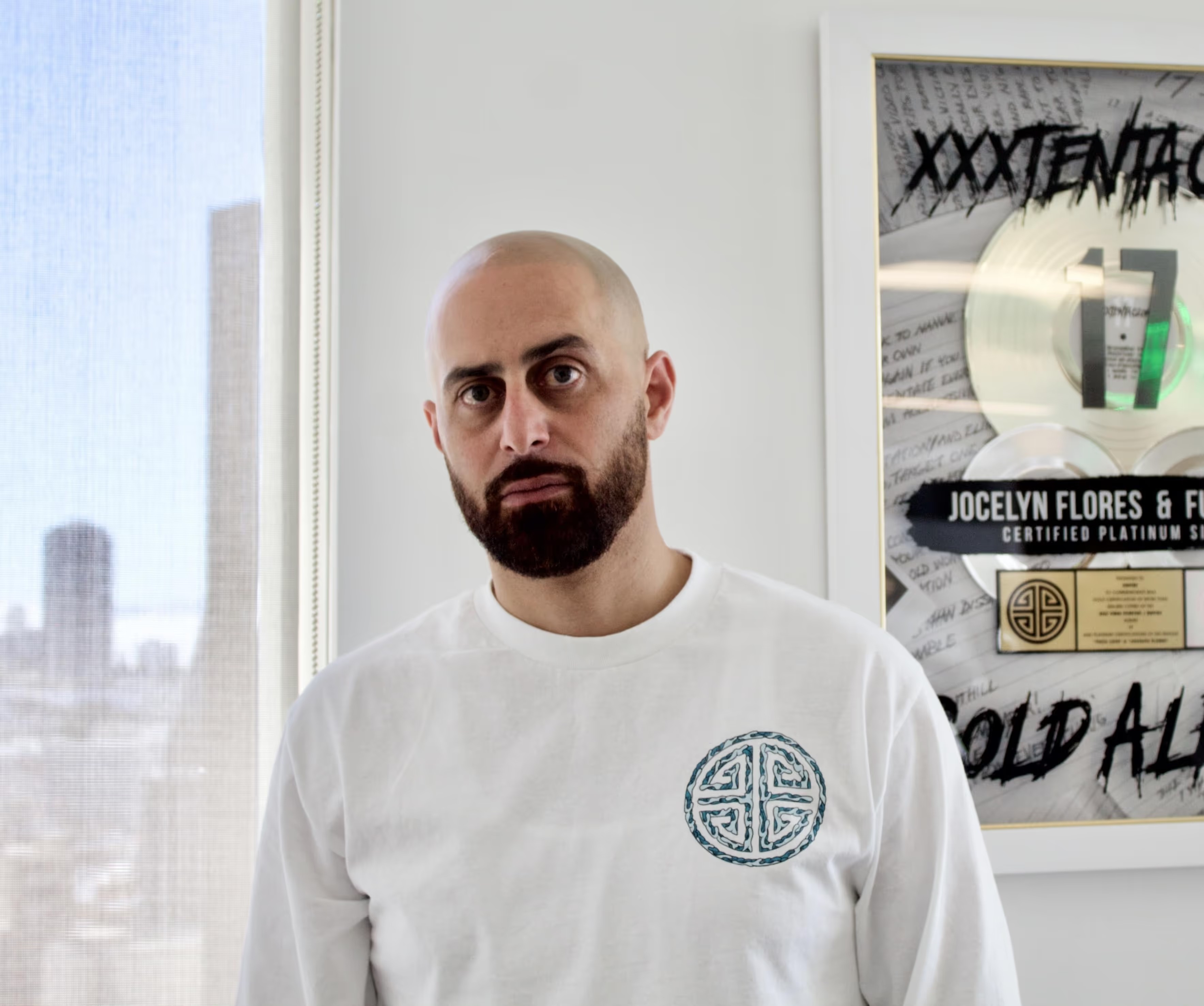 Ghazi Shami, founder and CEO of EMPIRE, standing beside a framed platinum record