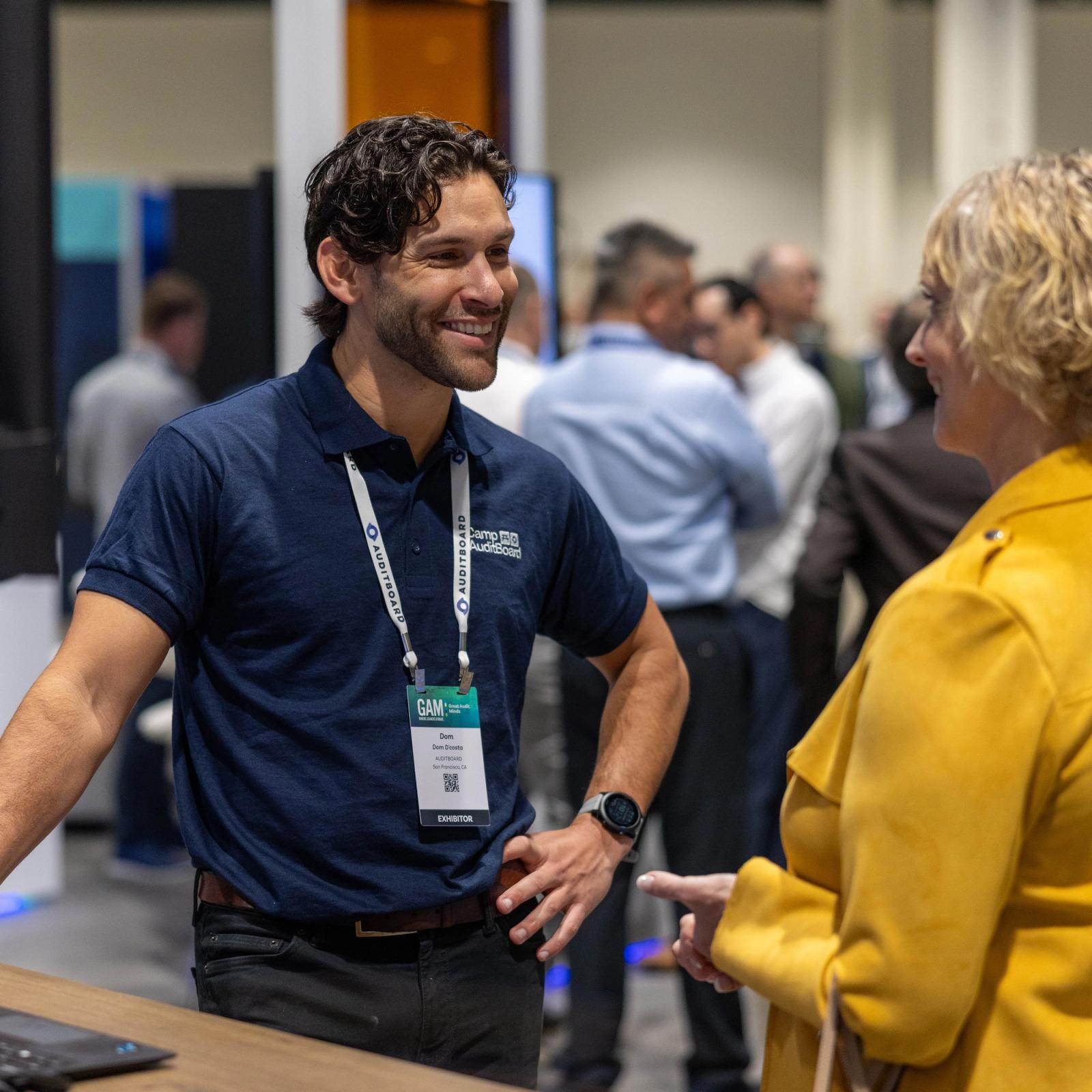 An AuditBoard representative talks with an attendee at an industry event