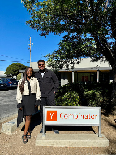 Audrey Djiya and Peter Nsaka standing beside a Y Combinator sign outdoors