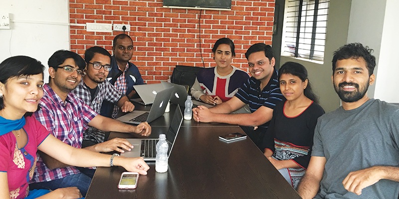The early CallHub team gathered around a conference table with laptops