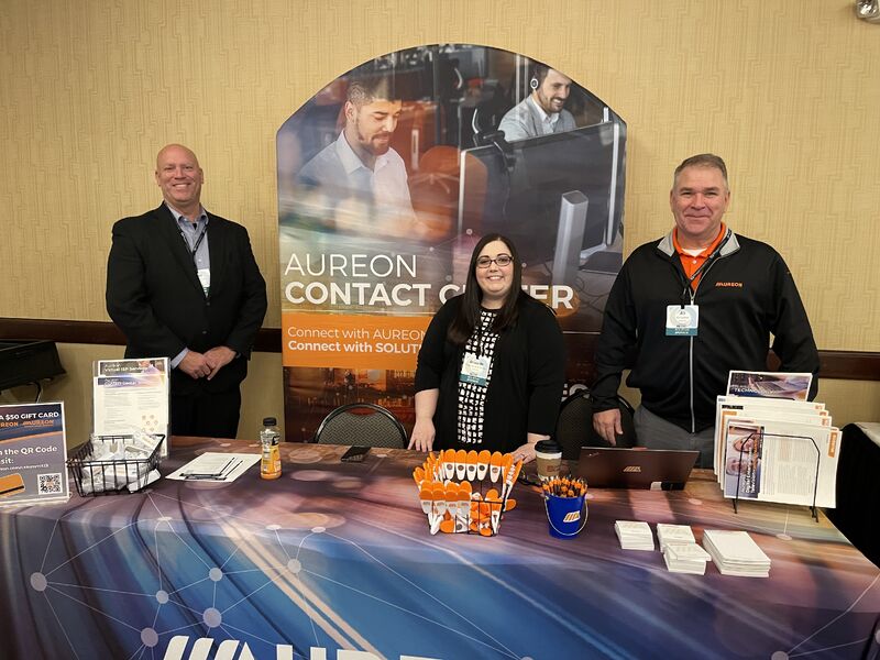 Three Aureon staff members behind their contact-center booth at the Iowa Communications Alliance CX Summit