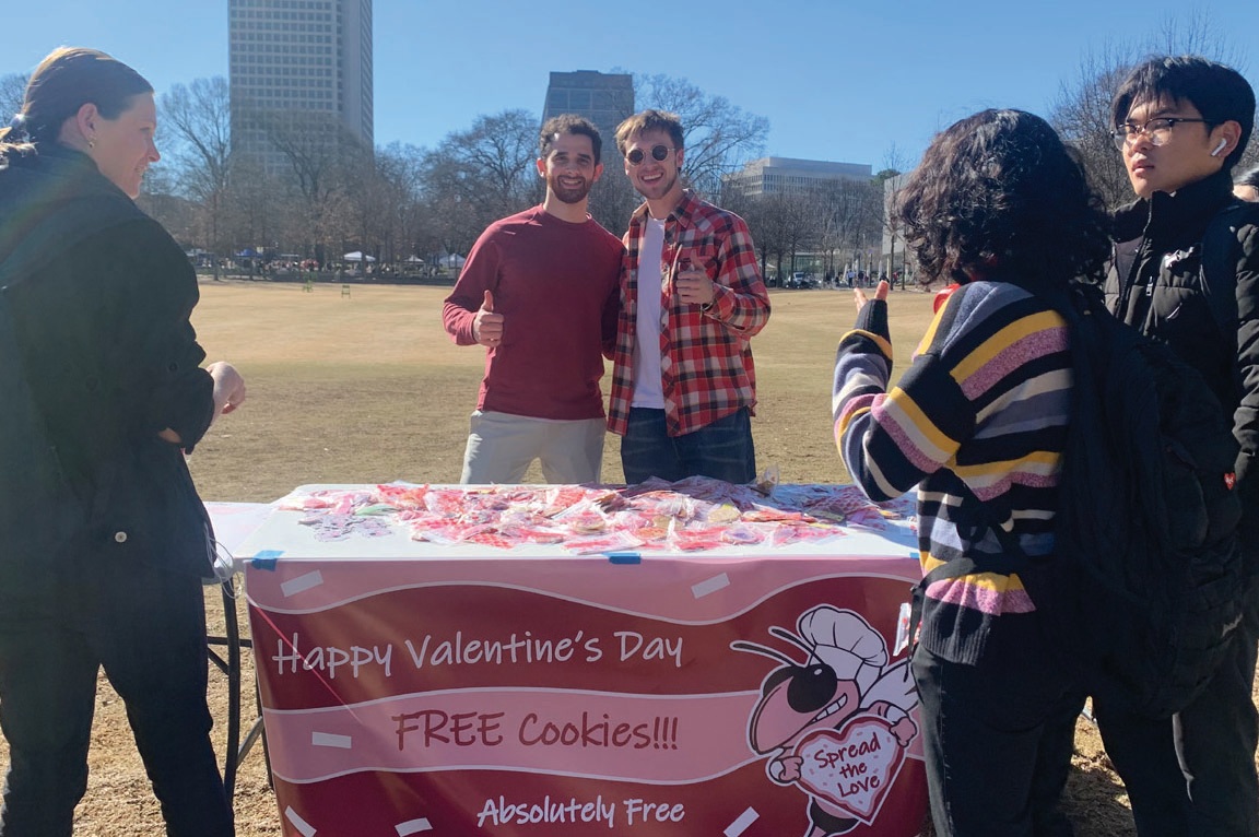 Austin Rowland and Jared Abrahamian standing behind a Georgia Tech table covered with free Valentine's Day cookies